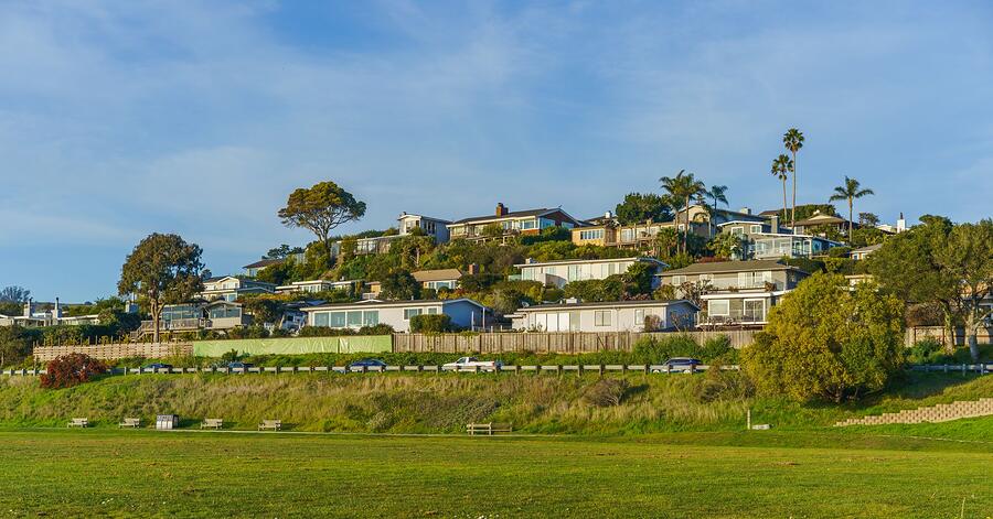 A California hillside neighborhood of houses among trees under a clear sky
