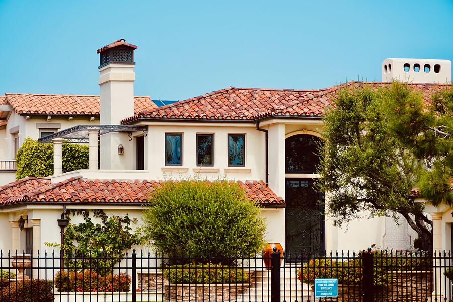 A Spanish revival house under a clay tile roof with mature planting, the Mission Hills type